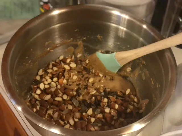 Gehackte Mandeln, Schokolade und kandierte Zitrusfrüchte werden auf den Teig gestreut, um sie unterzuheben.