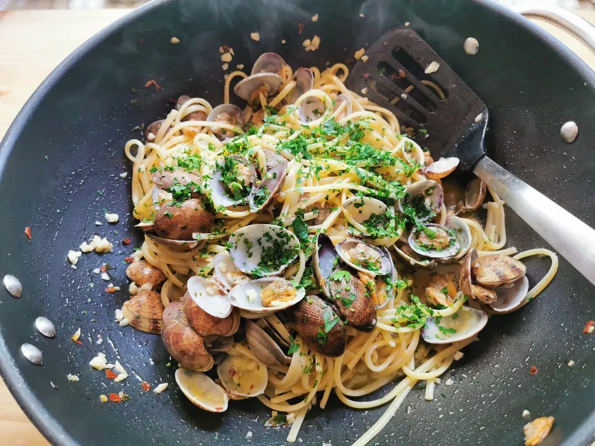 Gehackte Petersilie in Pfanne mit Linguine und Muscheln.