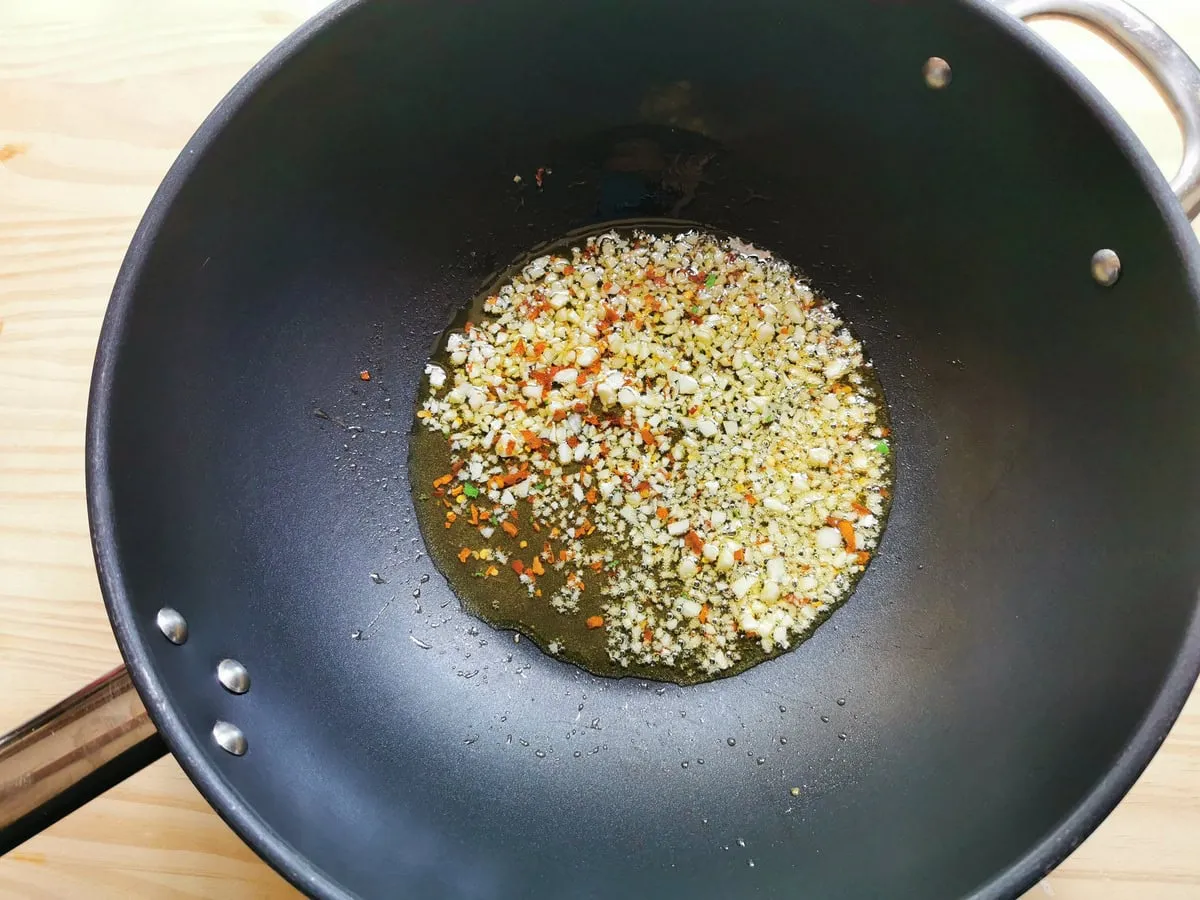 Gehackter Knoblauch und Peperoncino-Flocken braten in tiefer Bratpfanne.