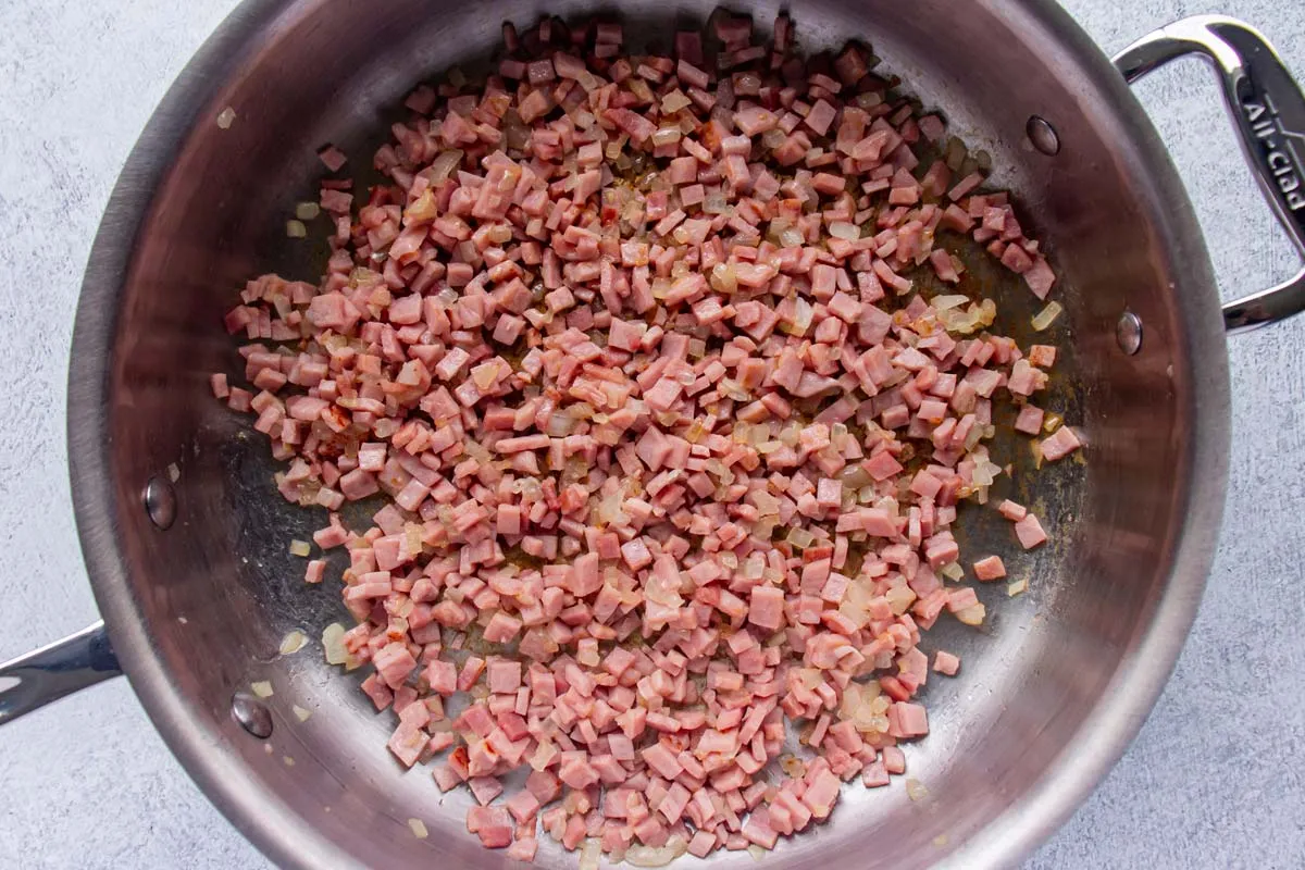 Gekochter gewürfelten Schinken und Zwiebeln in einer Edelstahlpfanne