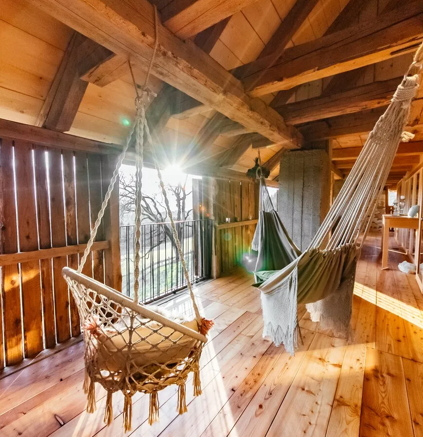 Gemütlicher Holzbalkon mit Hängesessel und Ausblick in die Natur