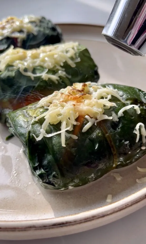 Geriebener Schweizer Käse wird über frisch gebackenen Capuns gegrillt