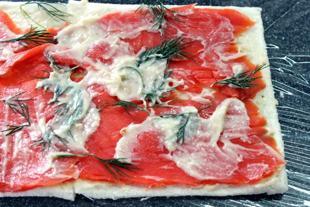 Gerollter Lachs-Toast auf Frischhaltefolie