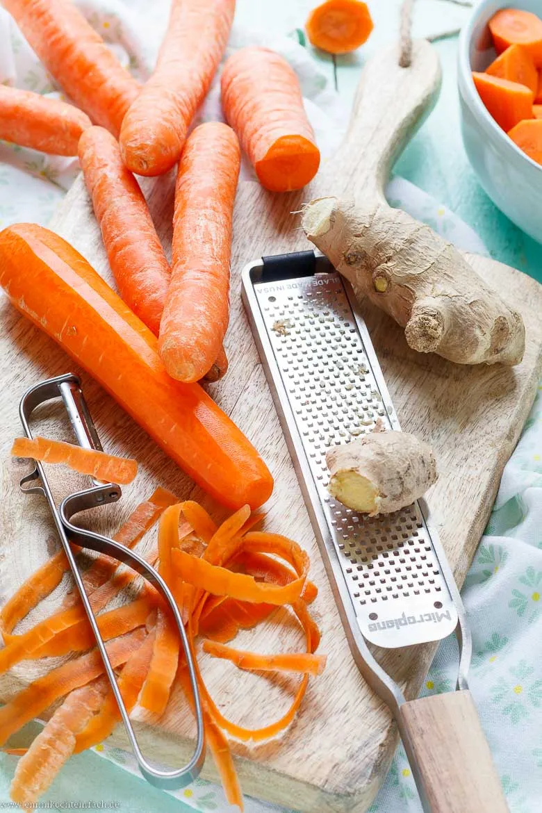 Gesunde Zutaten für die Möhren Ingwer Suppe auf einem rustikalen Holztisch