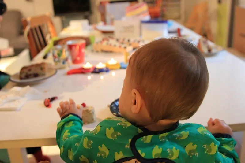 Glückliches Baby feiert ersten Geburtstag mit einem Stück zuckerfreiem Kuchen