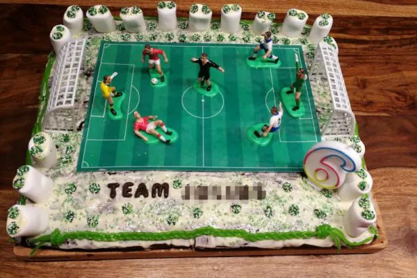 Glückliches Kind feiert seinen 6. Geburtstag mit dem selbstgemachten Fußballkuchen