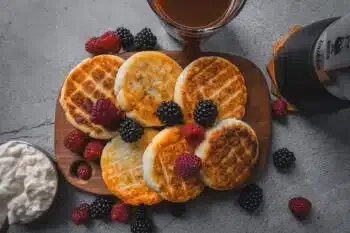 Goldbraune Syrniki Quarkküchlein, gestapelt und mit Beeren garniert