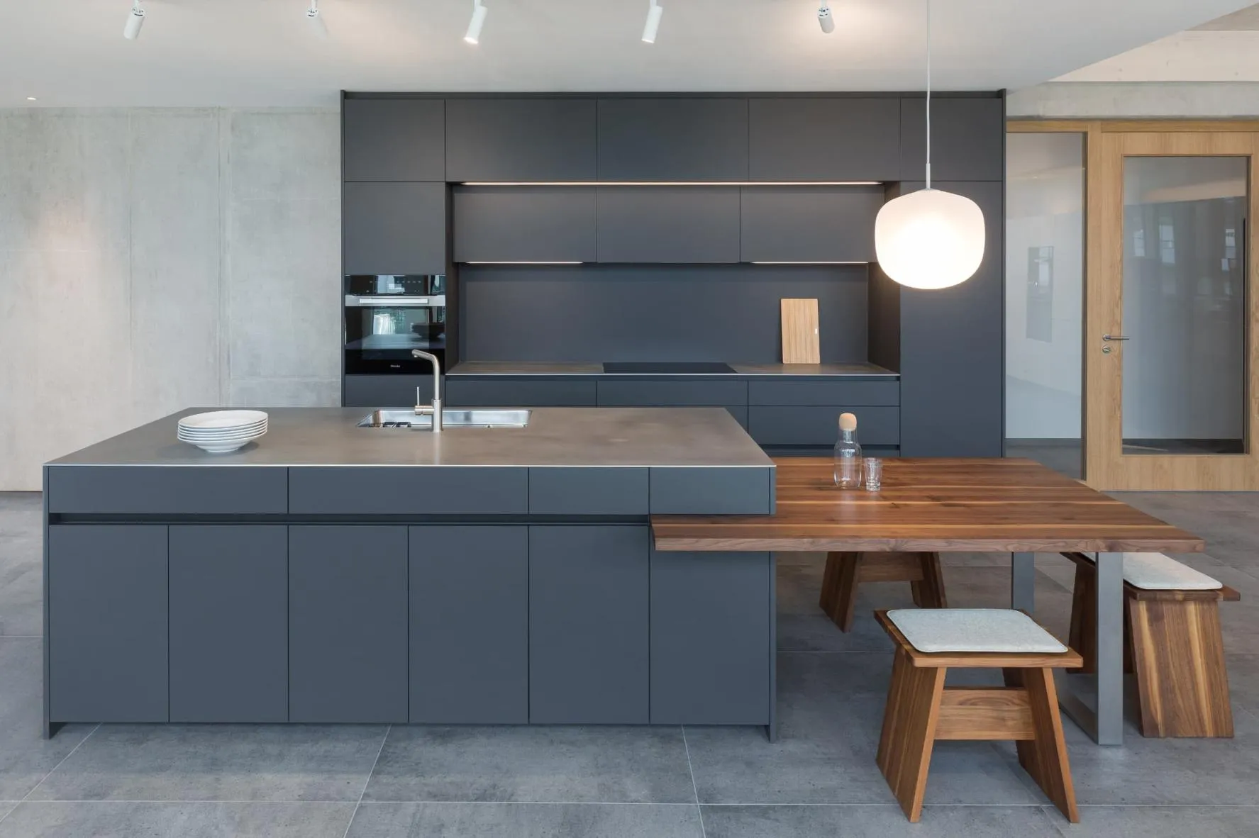 Graue Kücheninsel mit einer niedrigen, integrierten Sitzgelegenheit aus Holz