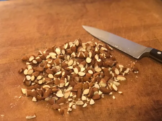 Grob gehackte Mandeln liegen auf einer Schneidefläche.