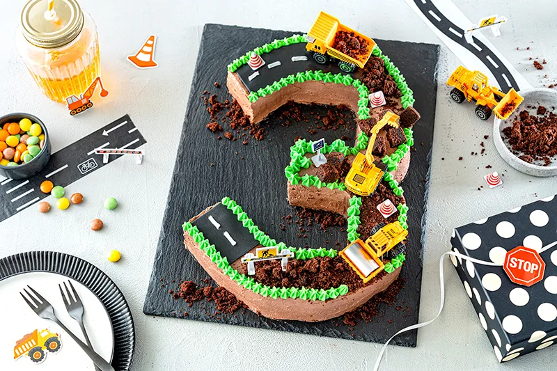 Grüne Sahnetupfer als Grasdekoration am Rand der Bagger-Torte