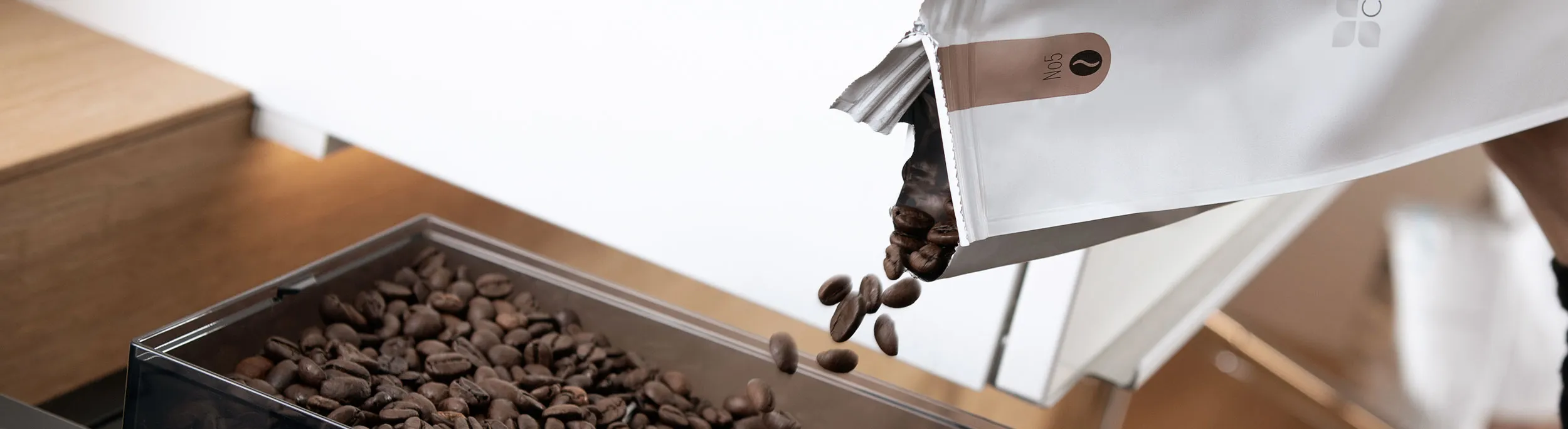 Hand füllt Kaffeebohnen in den Behälter eines Kaffeevollautomaten