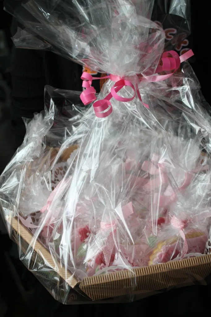 Hübsch verpackte Kekse in Fußform mit rosafarbenen Schleifen in einem dekorierten Korb