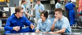 Industriefachkräfte in der Ausbildung diskutieren in einer Werkstatt