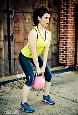 Junge Trainerin demonstriert eine Fitnessübung mit Fokus und Stärke