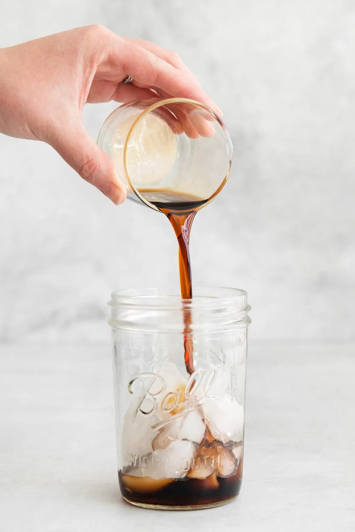 Kalten Espresso über Eis in ein Glas gießen