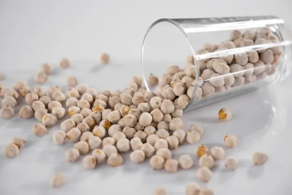 Kichererbsen fallen aus einem Glas auf einen Tisch