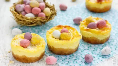 Kleine Käsekuchen-Muffins, festlich dekoriert mit Ostereiern, perfekt für die Ostertafel