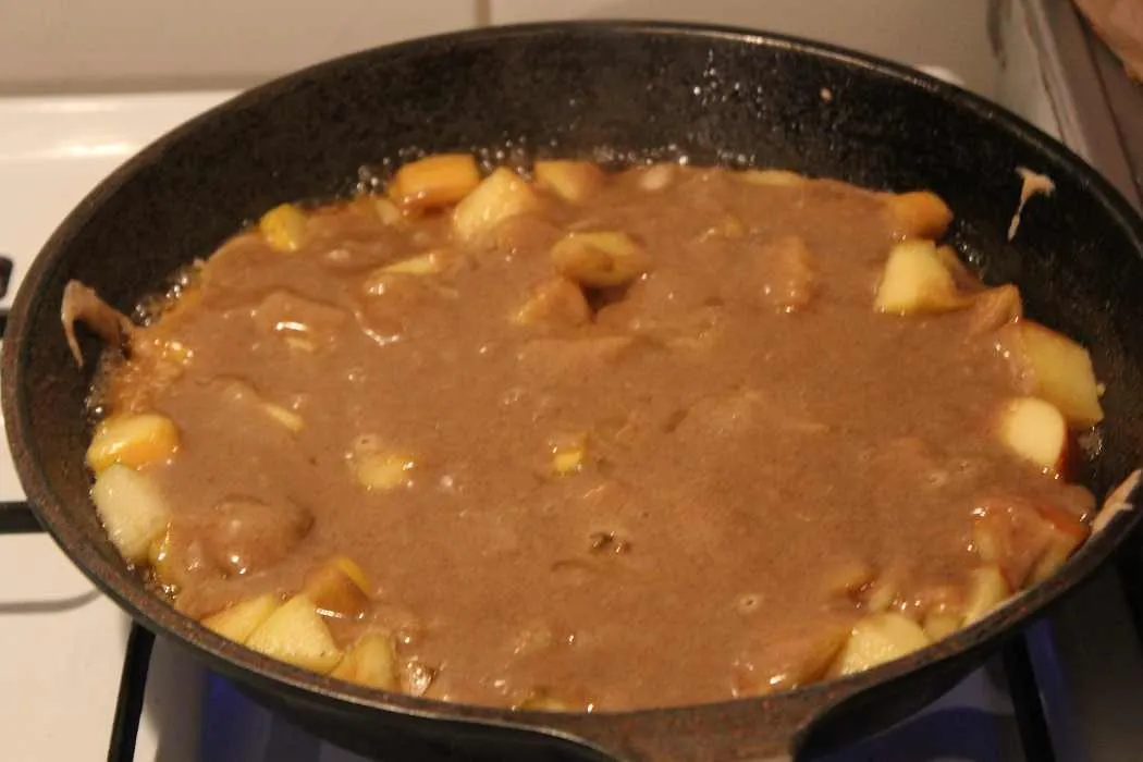 Kuchenteig wird über die Apfelmischung in die Pfanne gegossen