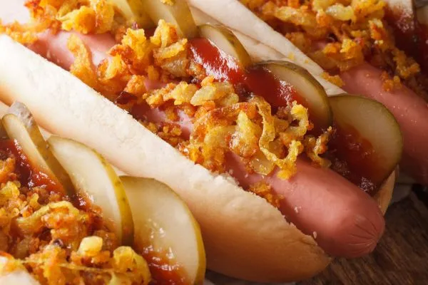 Leckere Mini Hot Dogs mit Gurken und Röstzwiebeln auf einer Party