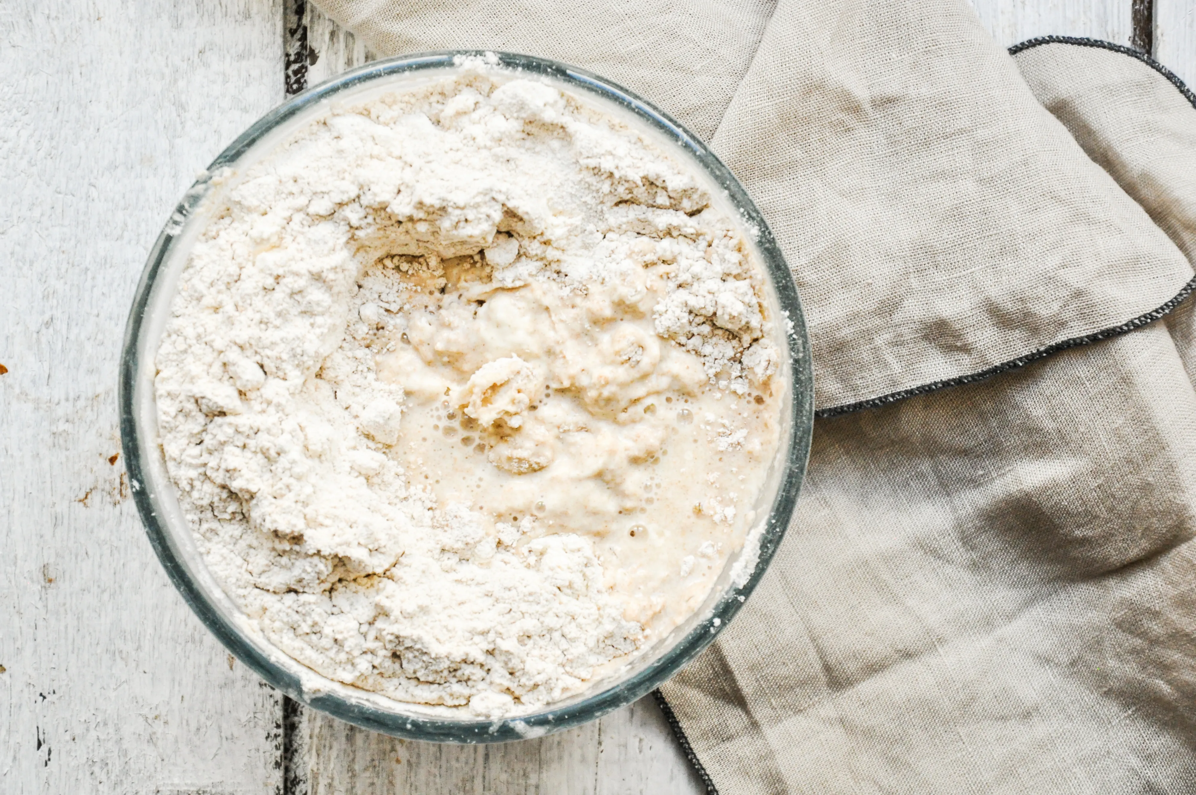 Mehl wird zum Sauerteigteig in der Schüssel hinzugefügt