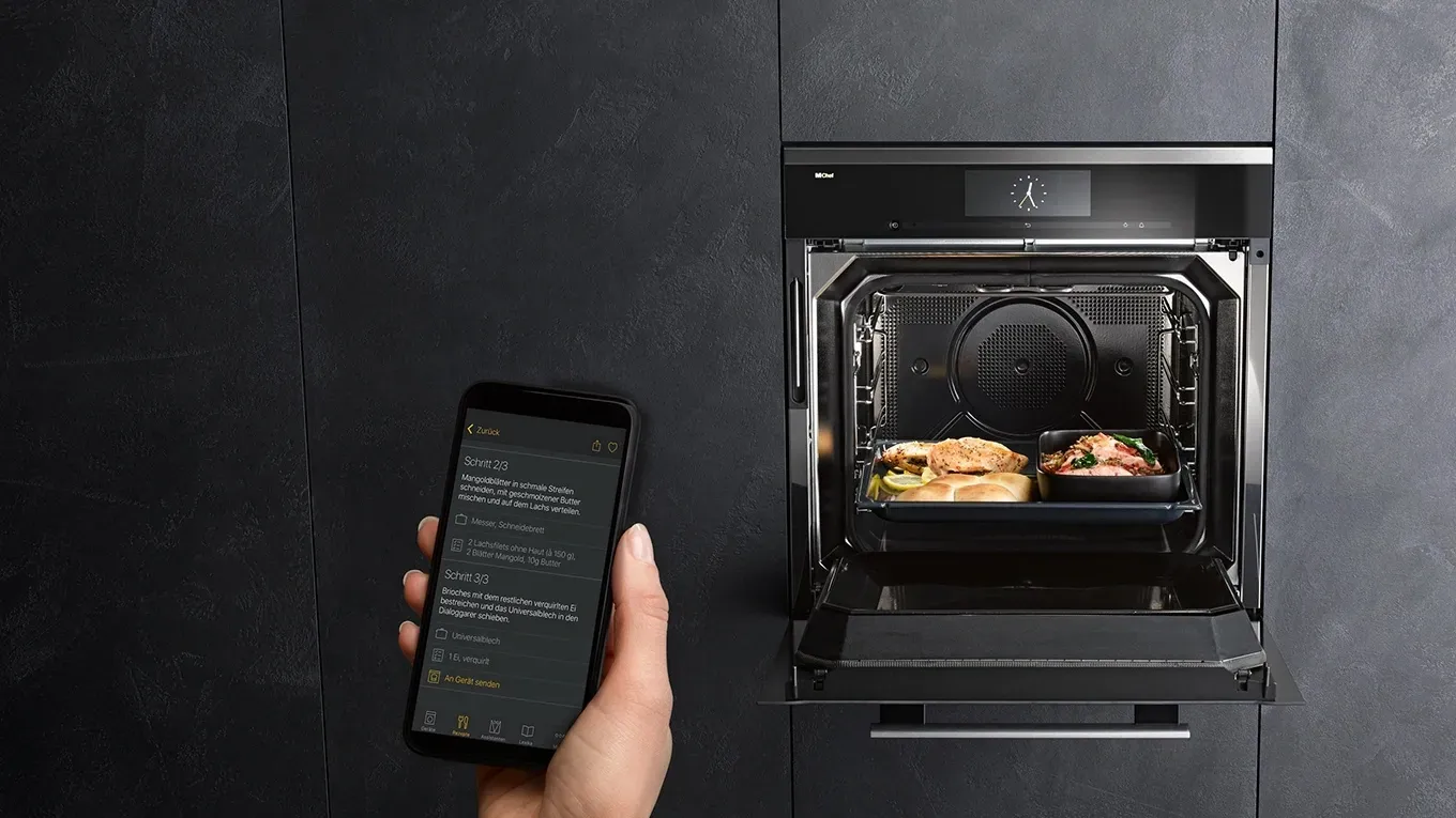 Miele Home Connect mit Smartphone vor geöffnetem Miele Backofen