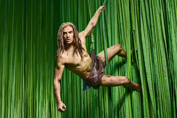 Musical Tarzan Darsteller vor Wand aus grünen Lianen