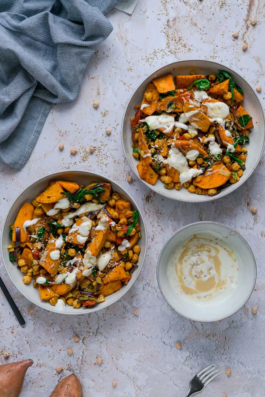 Nahaufnahme des fertigen Süßkartoffel-Kichererbsen-Blechs mit frischen Kräutern und Tahini-Dressing