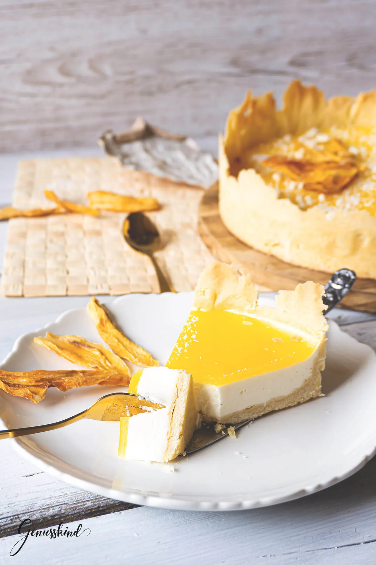 Nahaufnahme einer fertig dekorierten Mango-Joghurt-Torte mit Mangoscheiben und weißer Schokolade