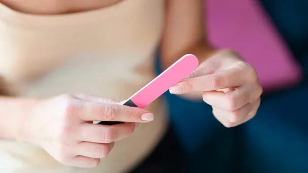 Nahaufnahme einer Frau, die sich die Fingernägel feilt