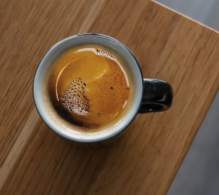 Nahaufnahme einer goldenen Crema auf einem frisch gebrühten Café Crema in einer Tasse