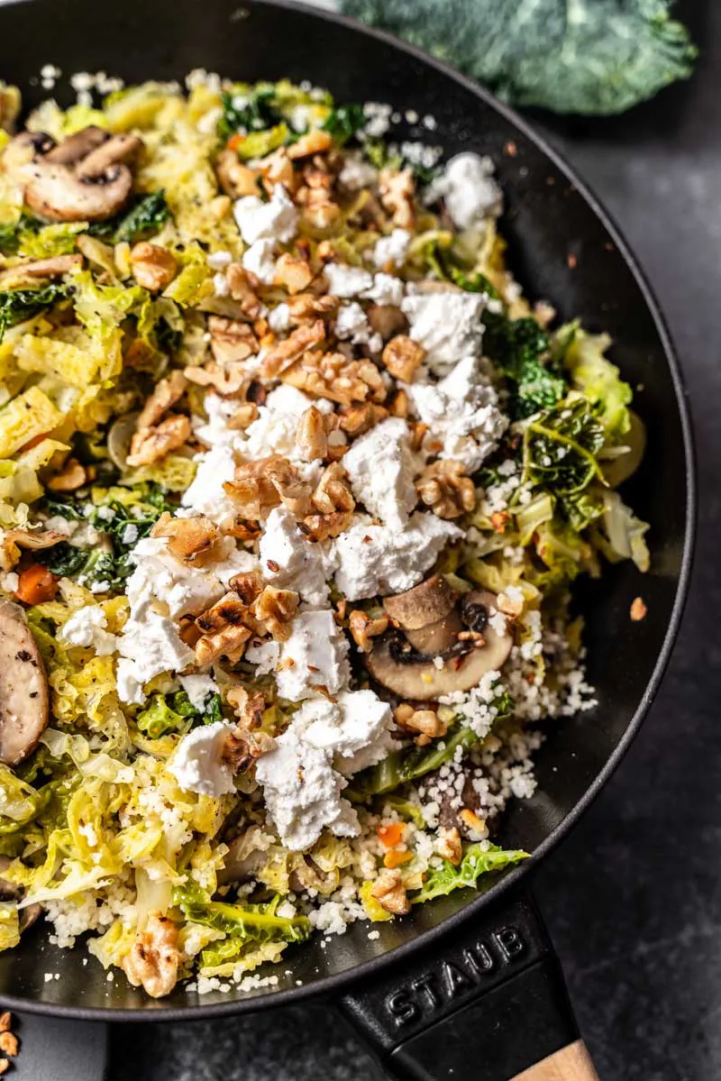 Nahaufnahme einer Portion Couscous-Pfanne mit Wirsing, Feta und Walnüssen