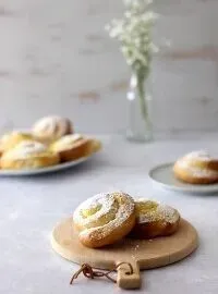 Nahaufnahme einer Puddingschnecke, bei der die Vanillepuddingfüllung deutlich sichtbar ist