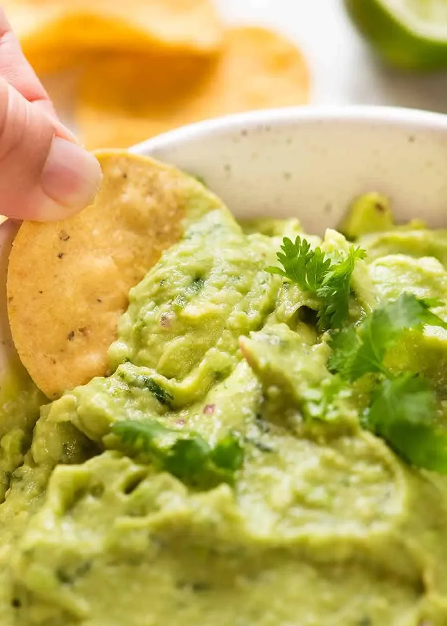 Nahaufnahme eines Maischips, der in Guacamole getaucht wird