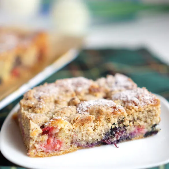 Nahaufnahme eines Stücks Beerenkuchen mit Nussstreuseln und frischen Beeren