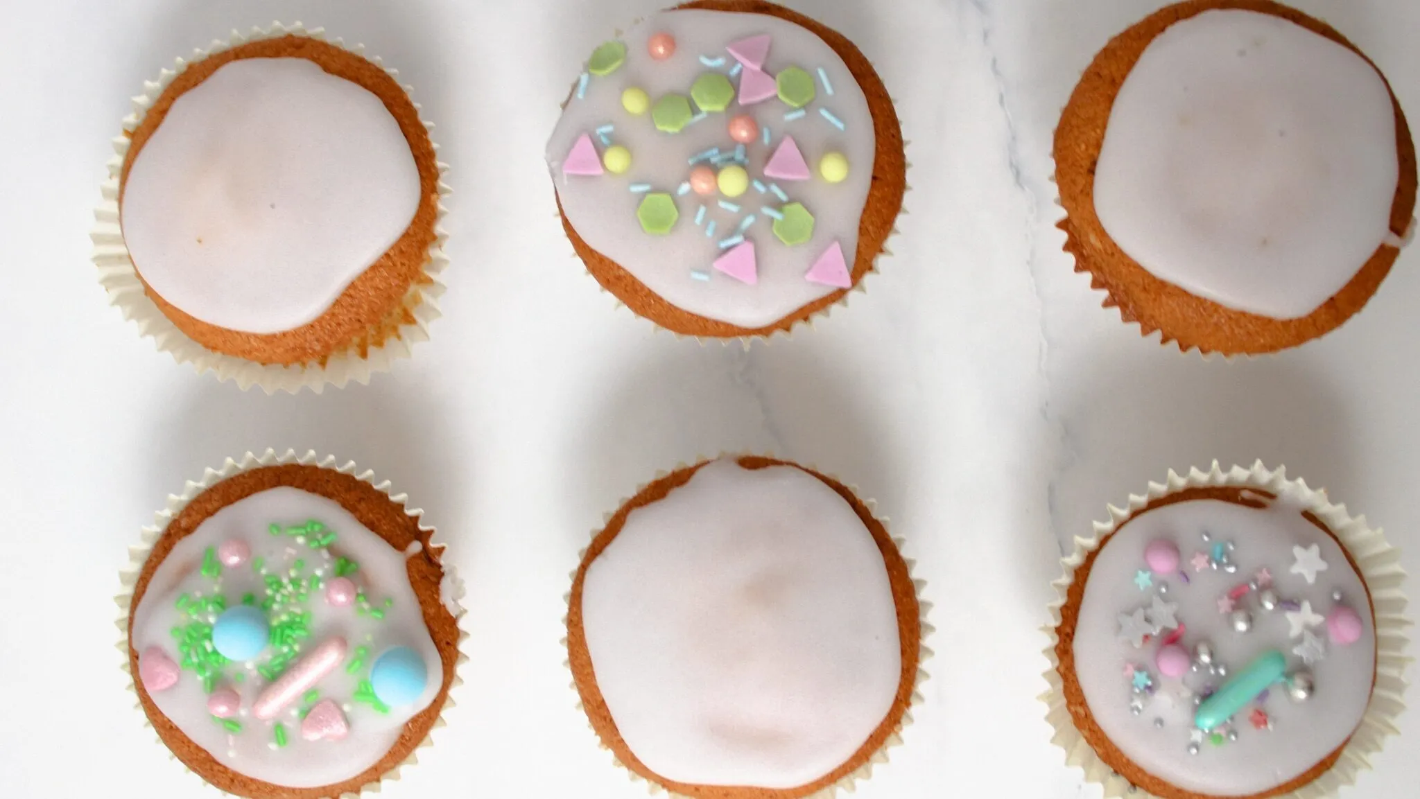 Nahaufnahme von einfachen Zitronenmuffins mit Glasur und bunten Streuseln