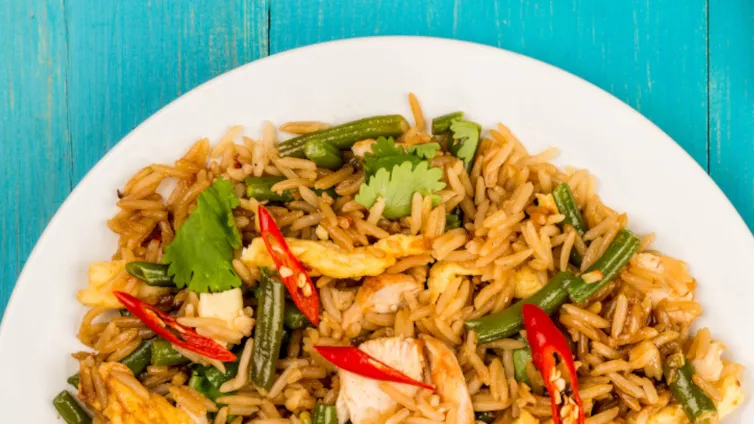 Nasi Goreng mit Hühnchen, Gemüse und Spiegelei in einer Schüssel