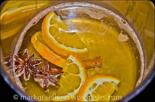 Orangenscheiben und Gewürze in einem Topf mit Wein