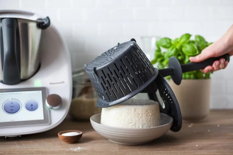 Perfekt gekochter Reis wird aus dem Garkorb direkt auf einen Teller gekippt.