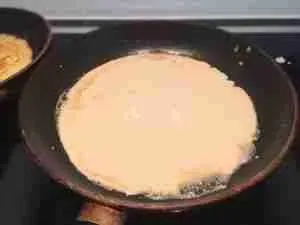 Pfannkuchenteig wird in eine heiße Pfanne gegossen