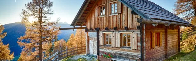 Romantische Almhütte im Herbst umgeben von bunter Landschaft