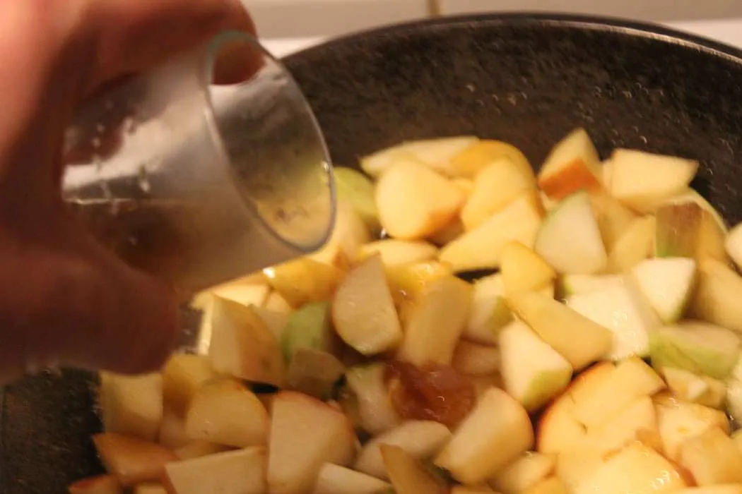 Rosinen werden zu den Äpfeln in die Pfanne gegeben
