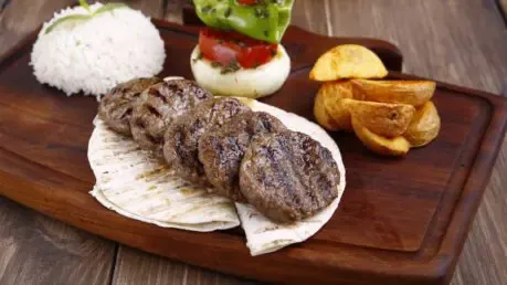 Saftige Köfte auf Fladenbrot mit Beilagen.