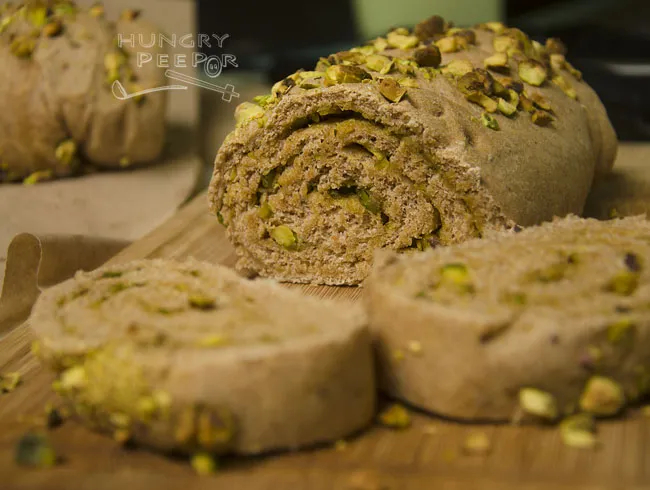 Schnitt eines gerollten Vollkornbrotes mit Pesto und Pistazien