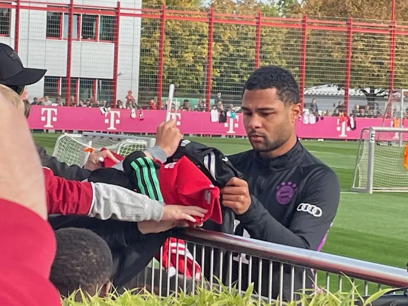 Serge Gnabry signiert Fan-Artikel während des Trainings