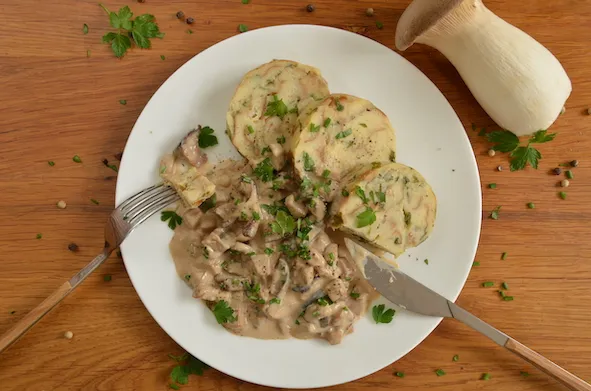 Serviettenknödel mit cremigem Pilzragout auf einem Teller