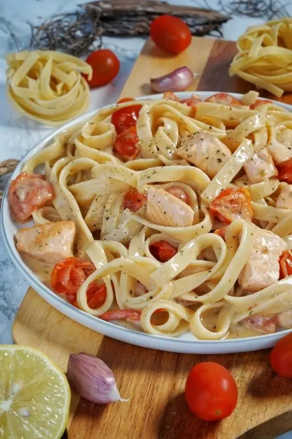 Tagliatelle mit Lachs und Tomaten auf einem Teller serviert