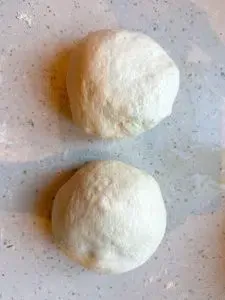 Teigkugeln für Fladenbrot auf einem mit Grieß bestreuten Backblech