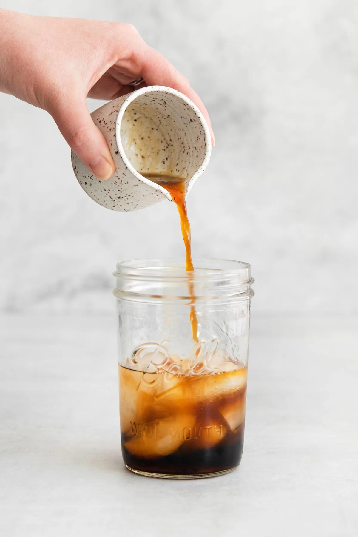 Tia Maria über Eis in ein Glas gießen