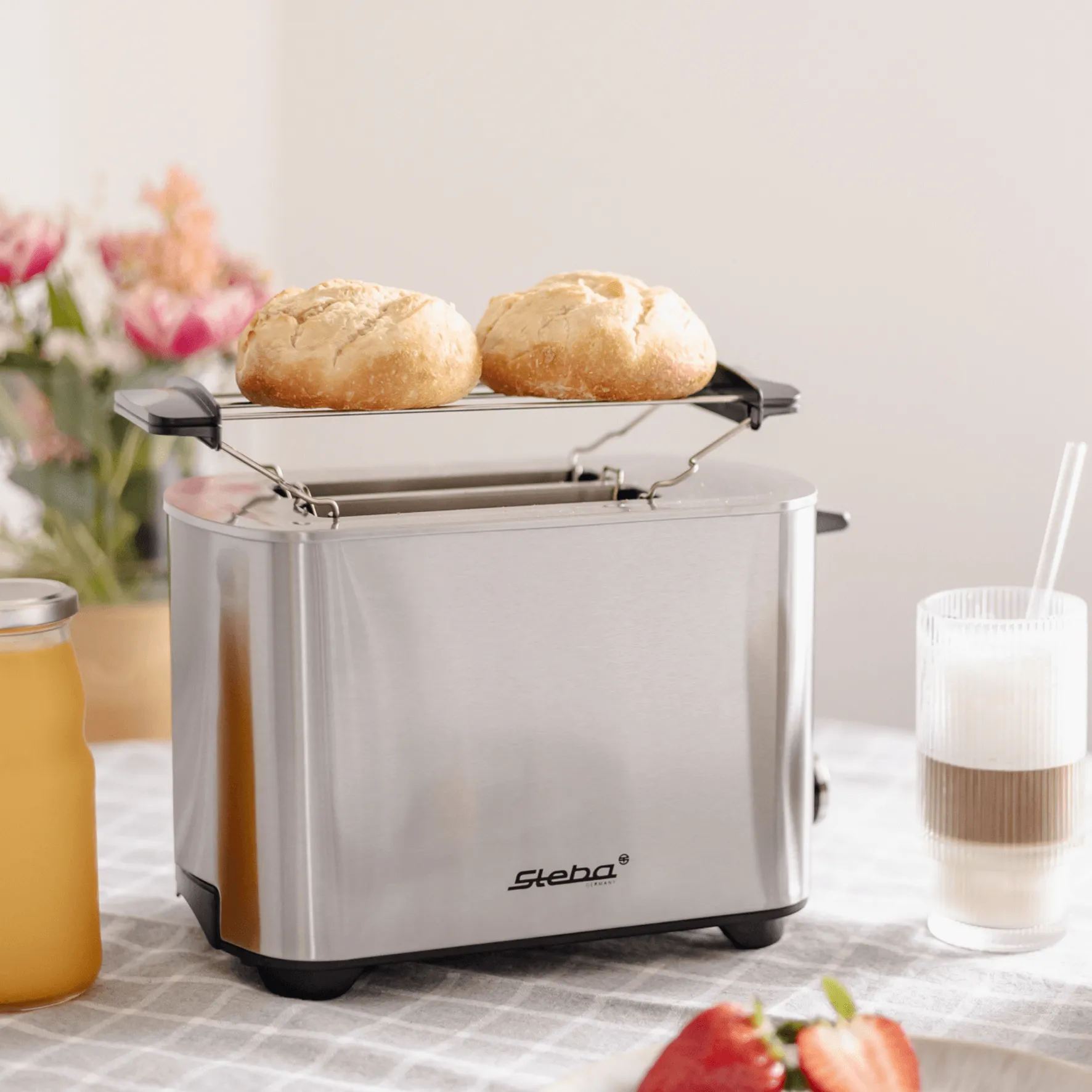 Toaster von Steba mit zwei Brötchen auf einem Einsatz. Edelstahl-Design, ideal für Frühstück.