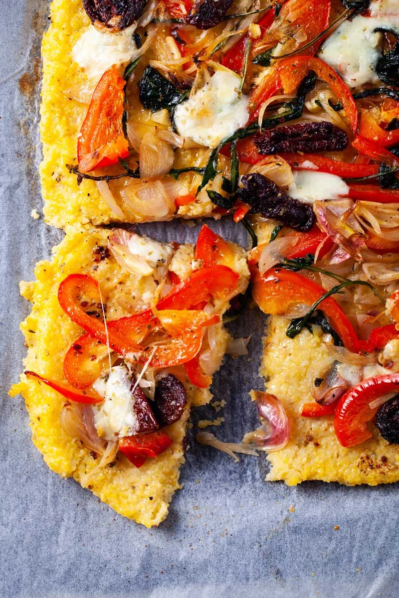 Vegetarische Polenta Pizza mit Spinat, Paprika, getrockneten Tomaten, Zwiebeln, Knoblauch und Mozzarella